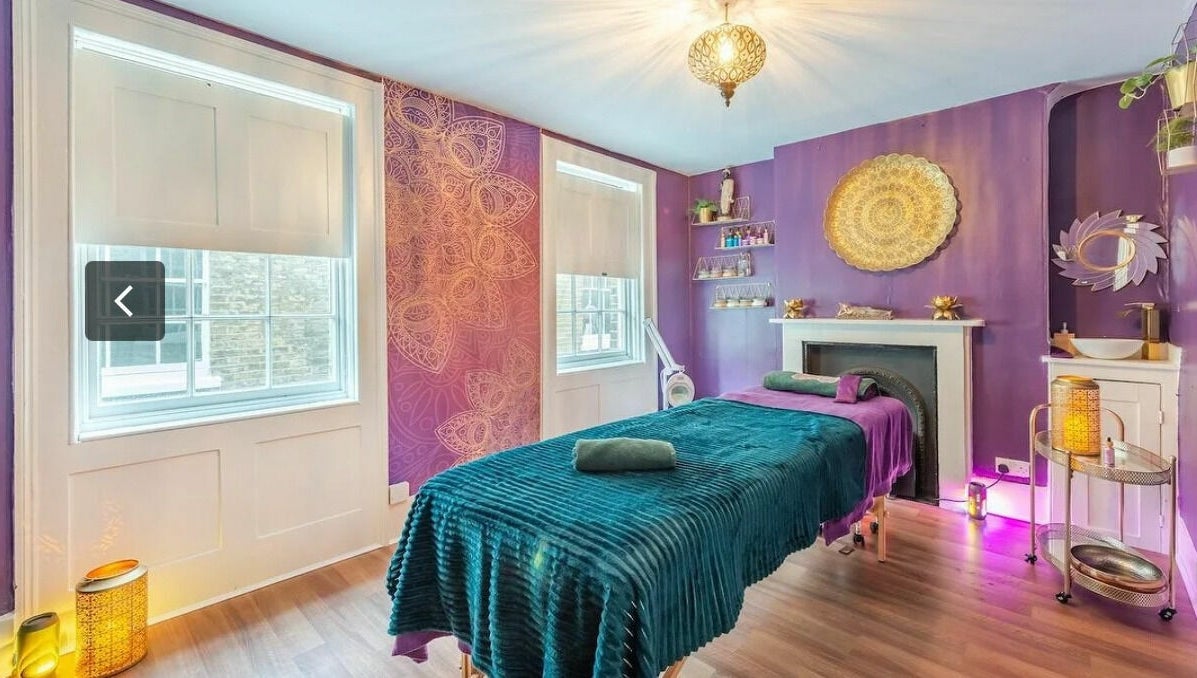 Tranquil treatment room at Aura Organics Spa - Greenwich, London, England, GB with purple decor and ambient lighting.