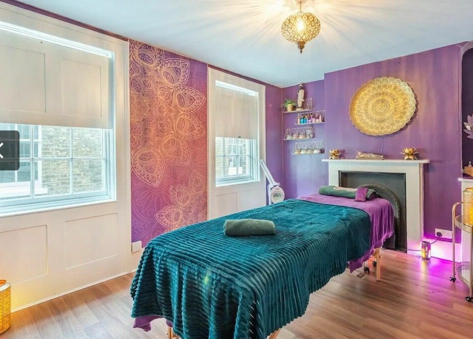 Tranquil treatment room at Aura Organics Spa - Greenwich, London, England, GB with purple decor and ambient lighting.