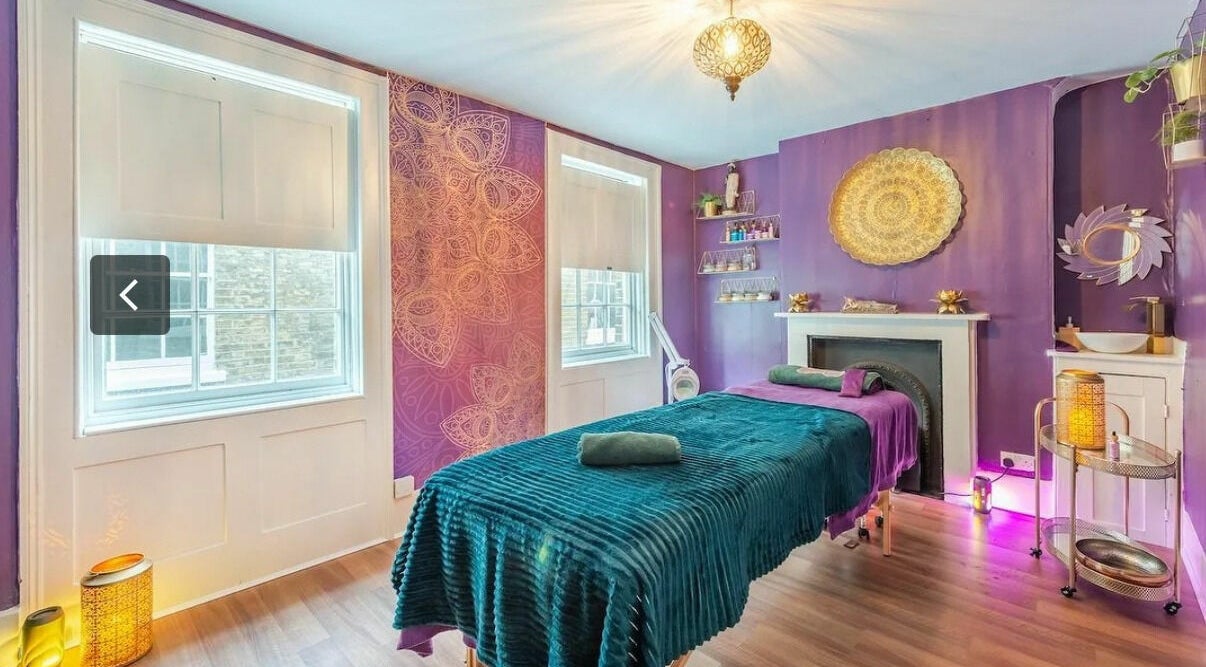 Tranquil treatment room at Aura Organics Spa - Greenwich, London, England, GB with purple decor and ambient lighting.