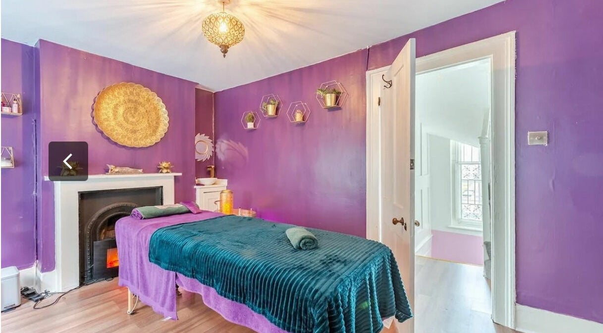Relaxing violet-hued massage room at Aura Organics Spa - Greenwich, London, England, GB showcasing serene ambiance.