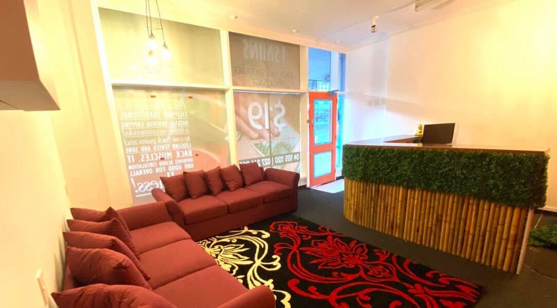 Cozy reception area at Bamboo Spa Lower Hutt Wellington showcasing a red sofa and bamboo-themed decor in Lower Hutt, Wellington, NZ.