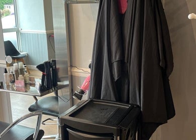 JB Hair salon styling station in Rode Heath, England, GB with tools and black capes.