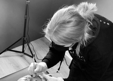 Beautician at ELR Cosmetics in Liverpool, England, GB skillfully enhancing client's eyebrows wearing mask and gloves.
