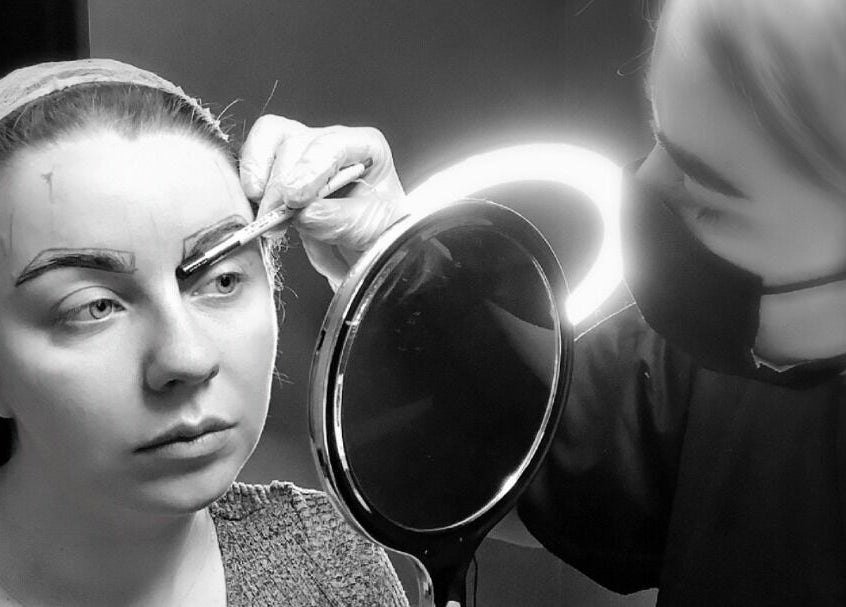 A beautician at ELR Cosmetics in Liverpool, England, GB, expertly shaping eyebrows with precision tools.