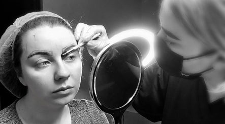 A beautician at ELR Cosmetics in Liverpool, England, GB, expertly shaping eyebrows with precision tools.