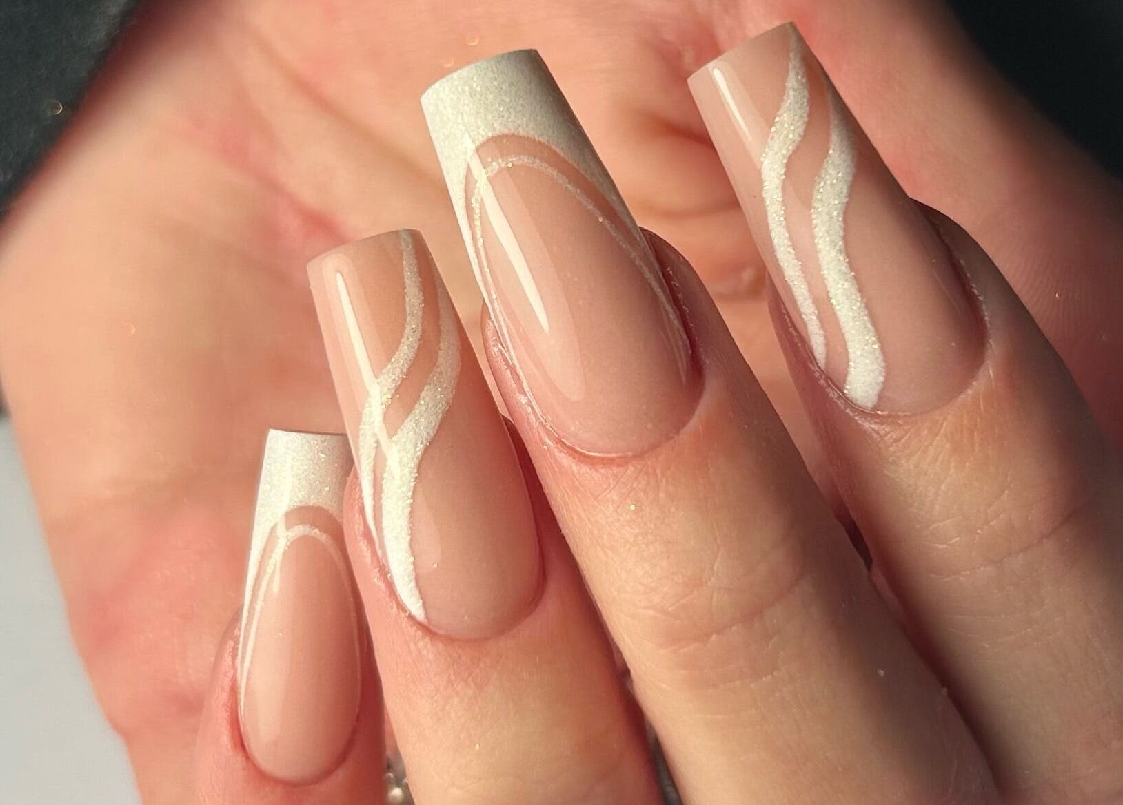Intricate nail art at Nails by Hallie, Four Lanes, England, GB. Elegant design with nude and white swirls.
