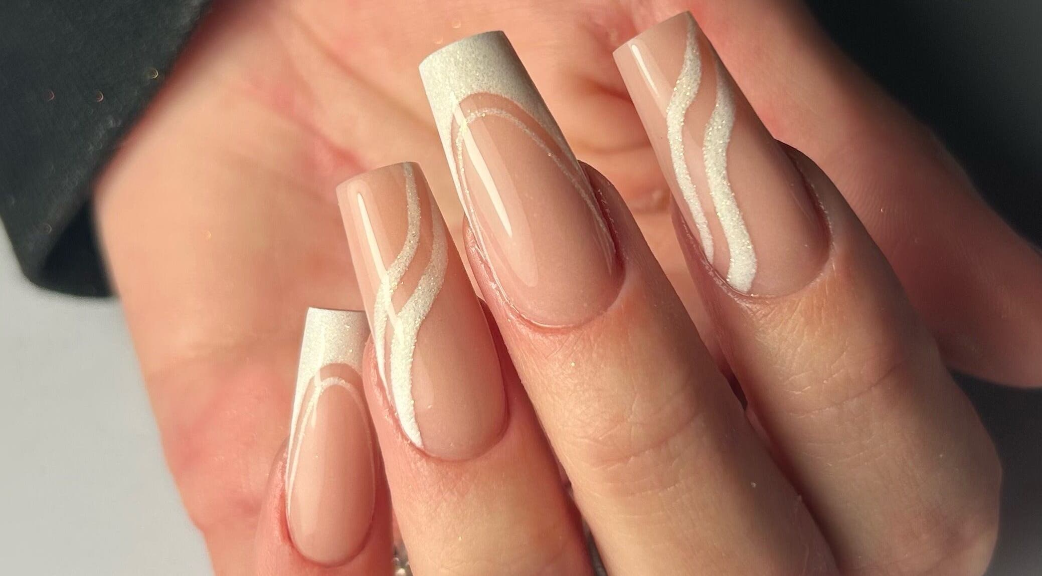 Intricate nail art at Nails by Hallie, Four Lanes, England, GB. Elegant design with nude and white swirls.