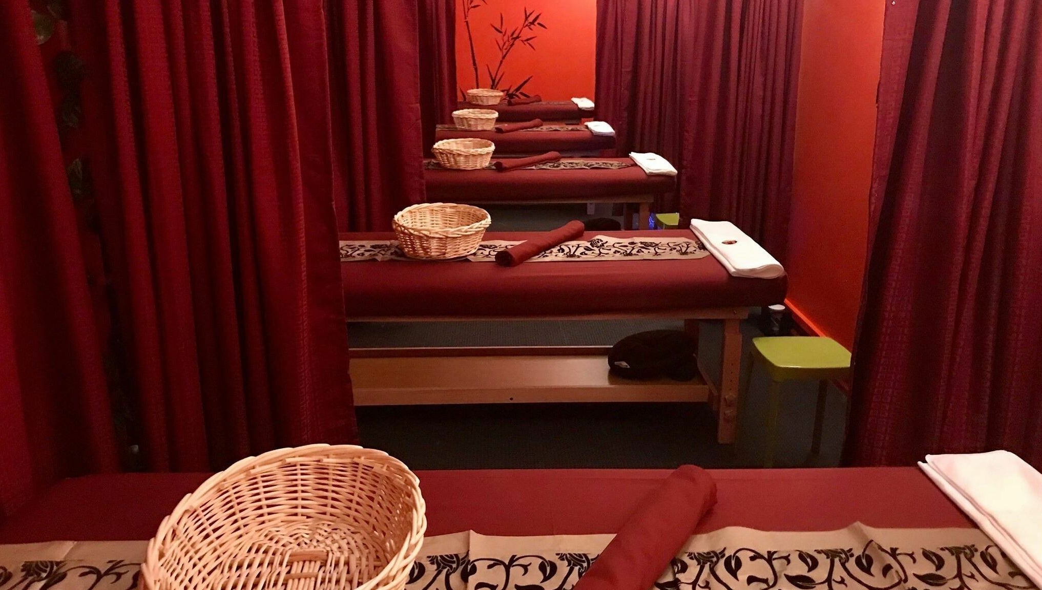 Relaxing massage tables at Bamboo Spa Hamilton, Hamilton, Waikato, NZ, with red curtains and calm ambiance.