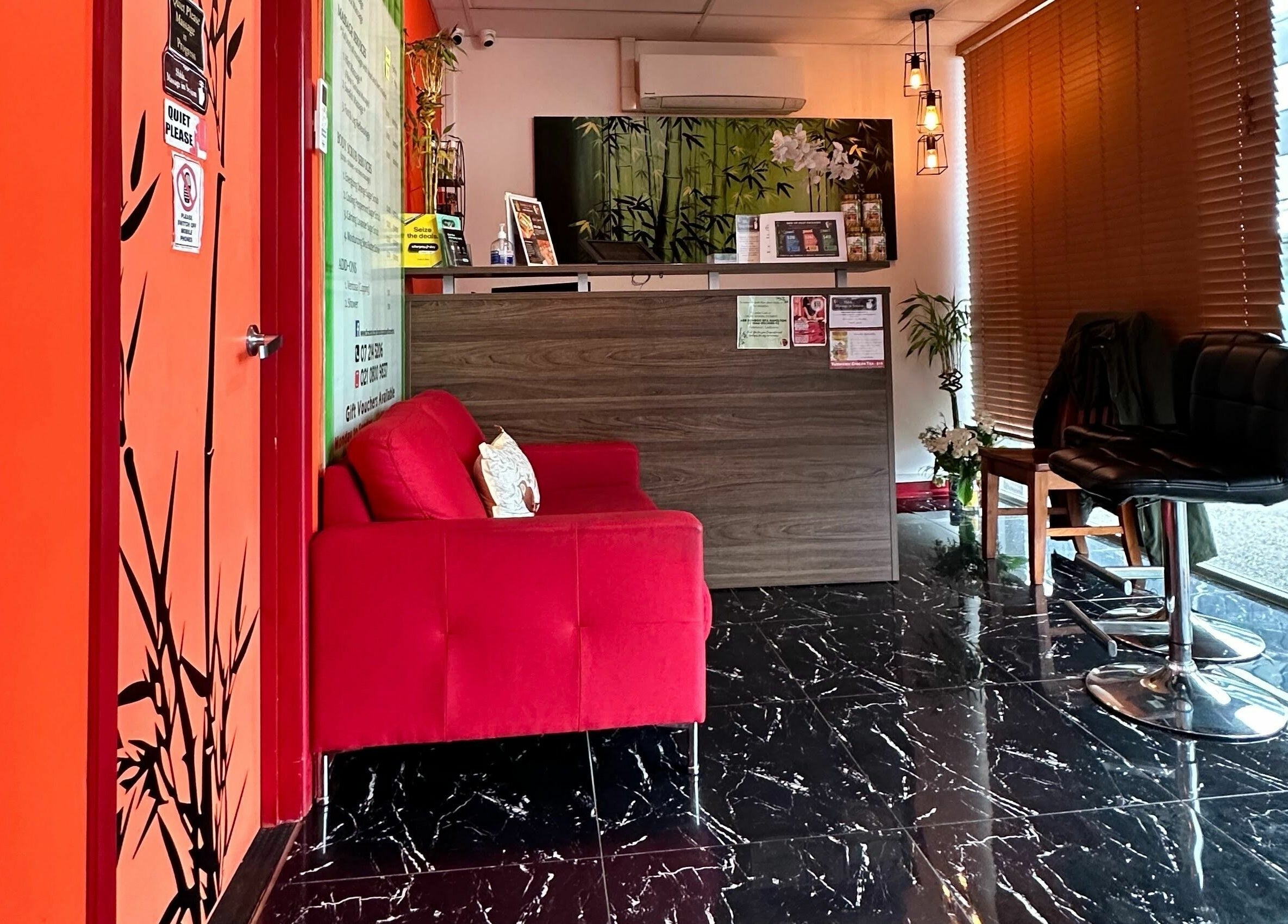 Bamboo Spa Hamilton's reception area in Hamilton, Waikato, NZ with a cozy red sofa and bamboo decor.