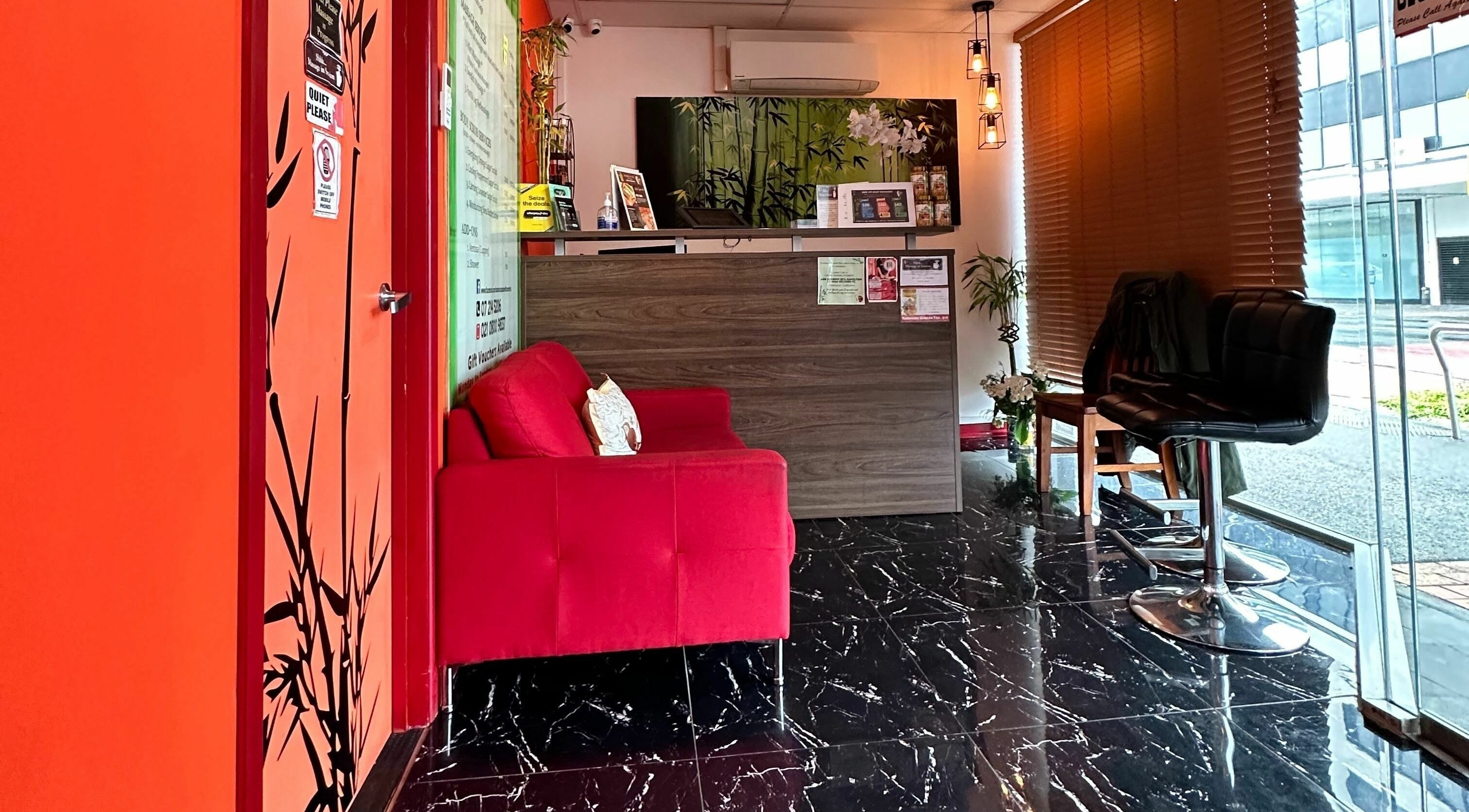 Bamboo Spa Hamilton's reception area in Hamilton, Waikato, NZ with a cozy red sofa and bamboo decor.