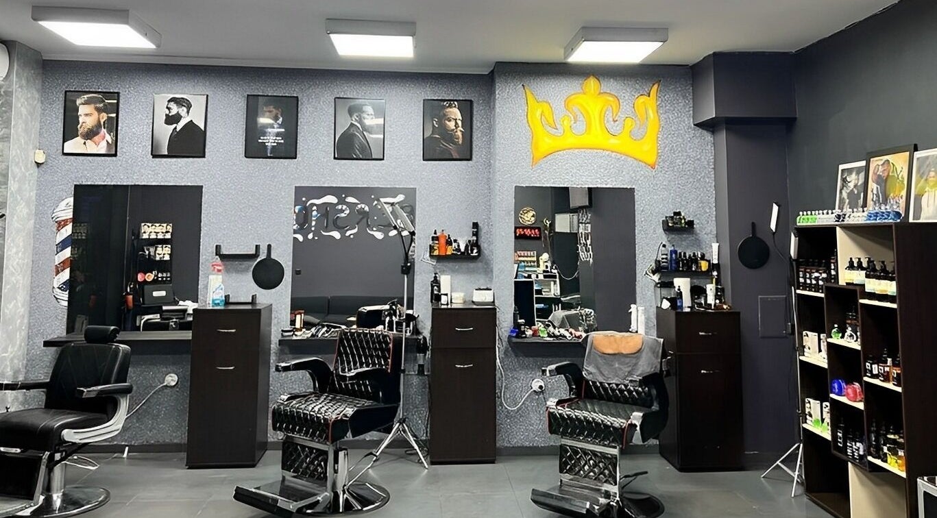 Интериор на King Barber, София, Софийска област, BG, показващ модерни столове и декор с корона.