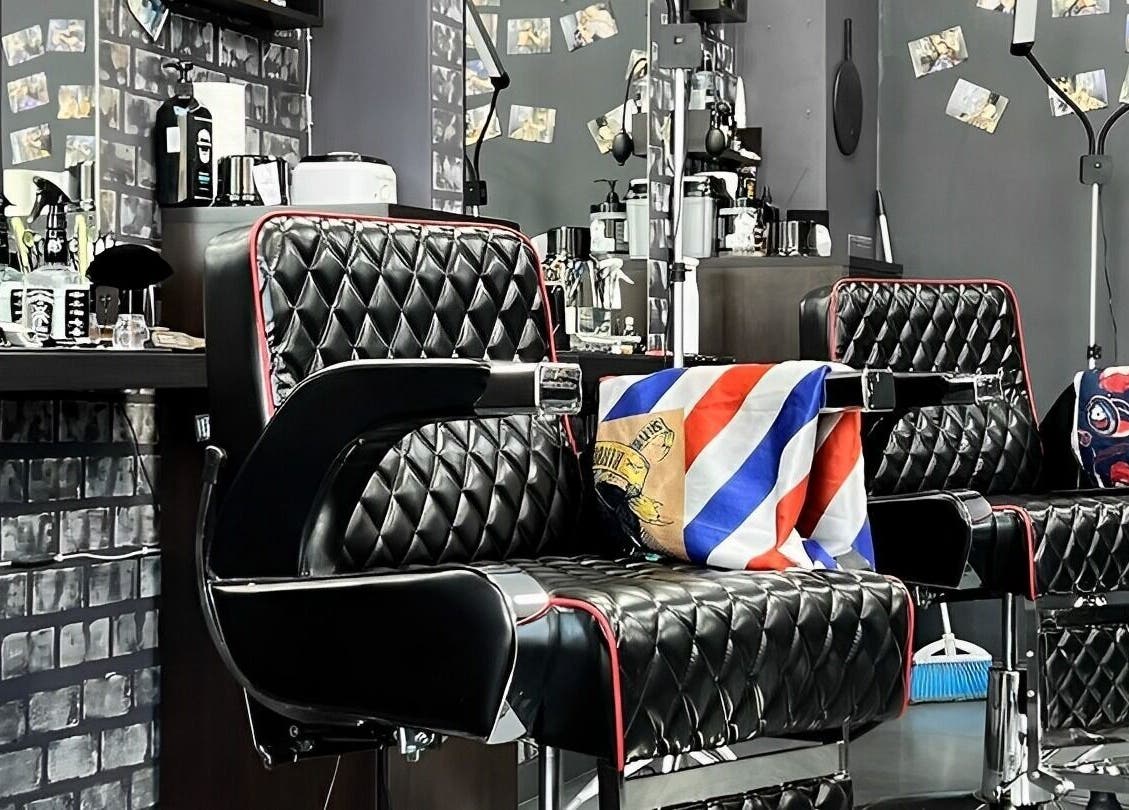 Интериор на King Barber, София, с черни кожени кресла и декориран ножицов флаг.