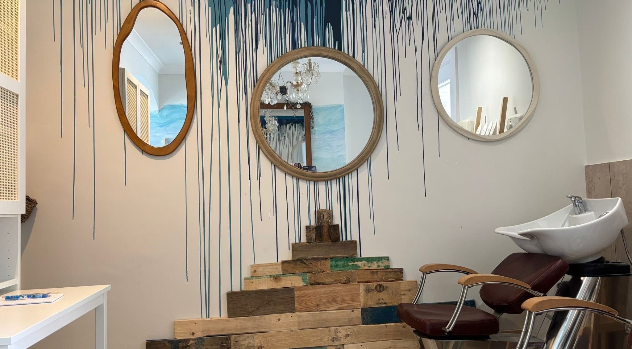 Unique mirror wall design at The Curl Girl Devon, Braunton, England, GB, with a modern salon chair and sink.