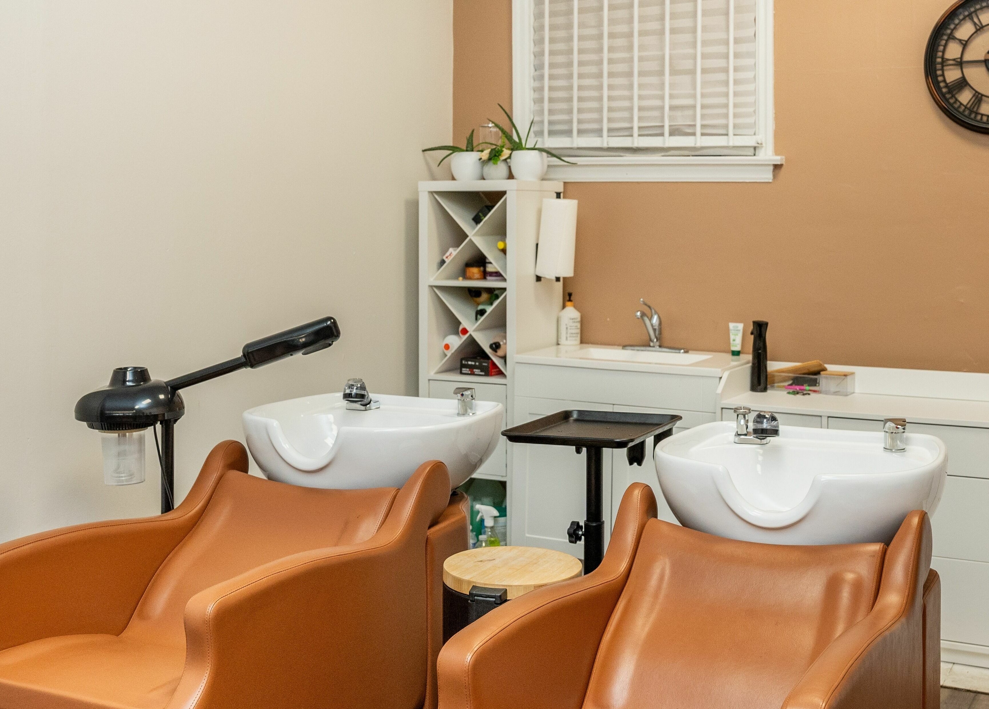 Stylish hair wash stations at Locs by Jiji in Toronto, Ontario, CA, featuring plush brown chairs and modern basins.