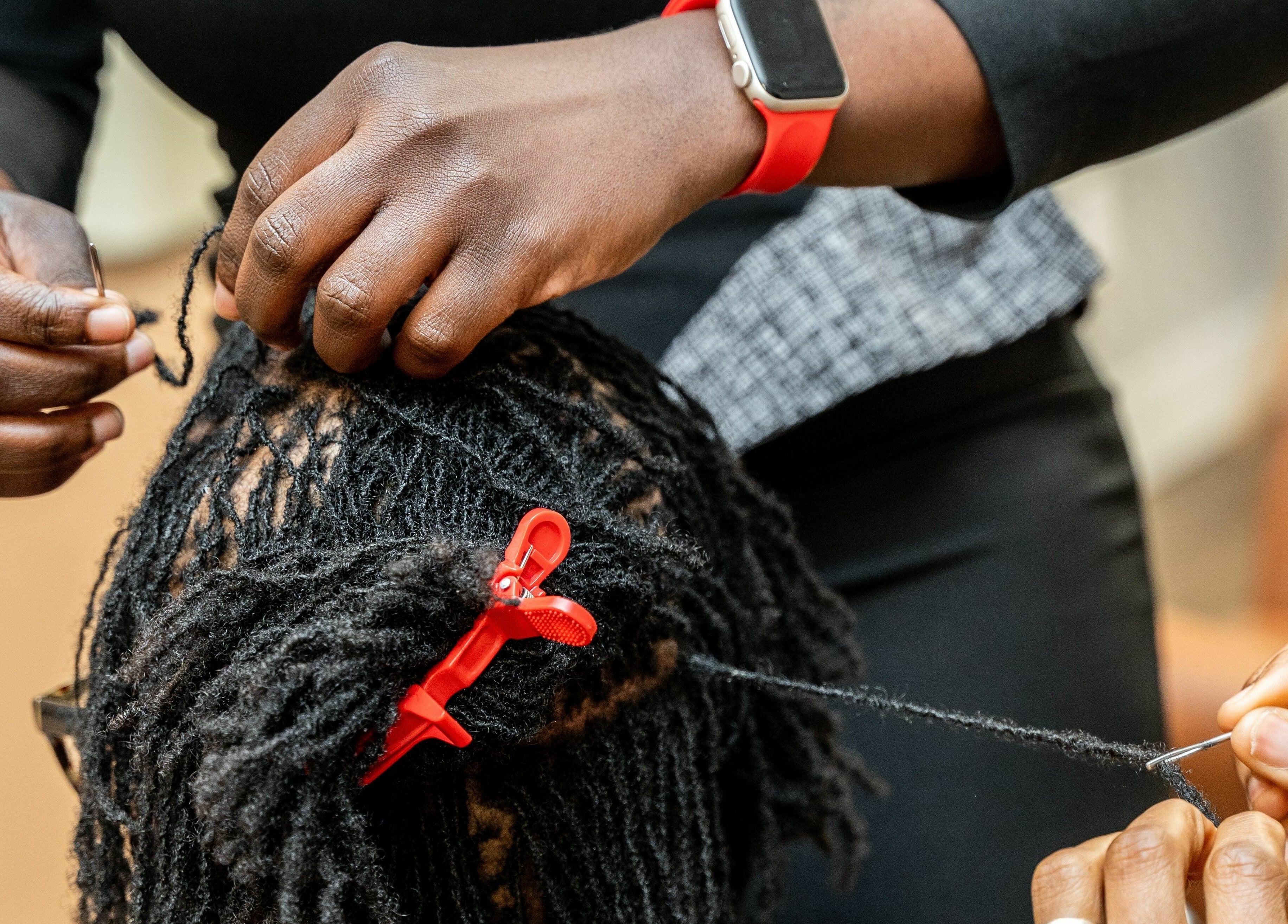 Stylist intricately weaving locs at Locs by Jiji, Toronto, Ontario, CA.