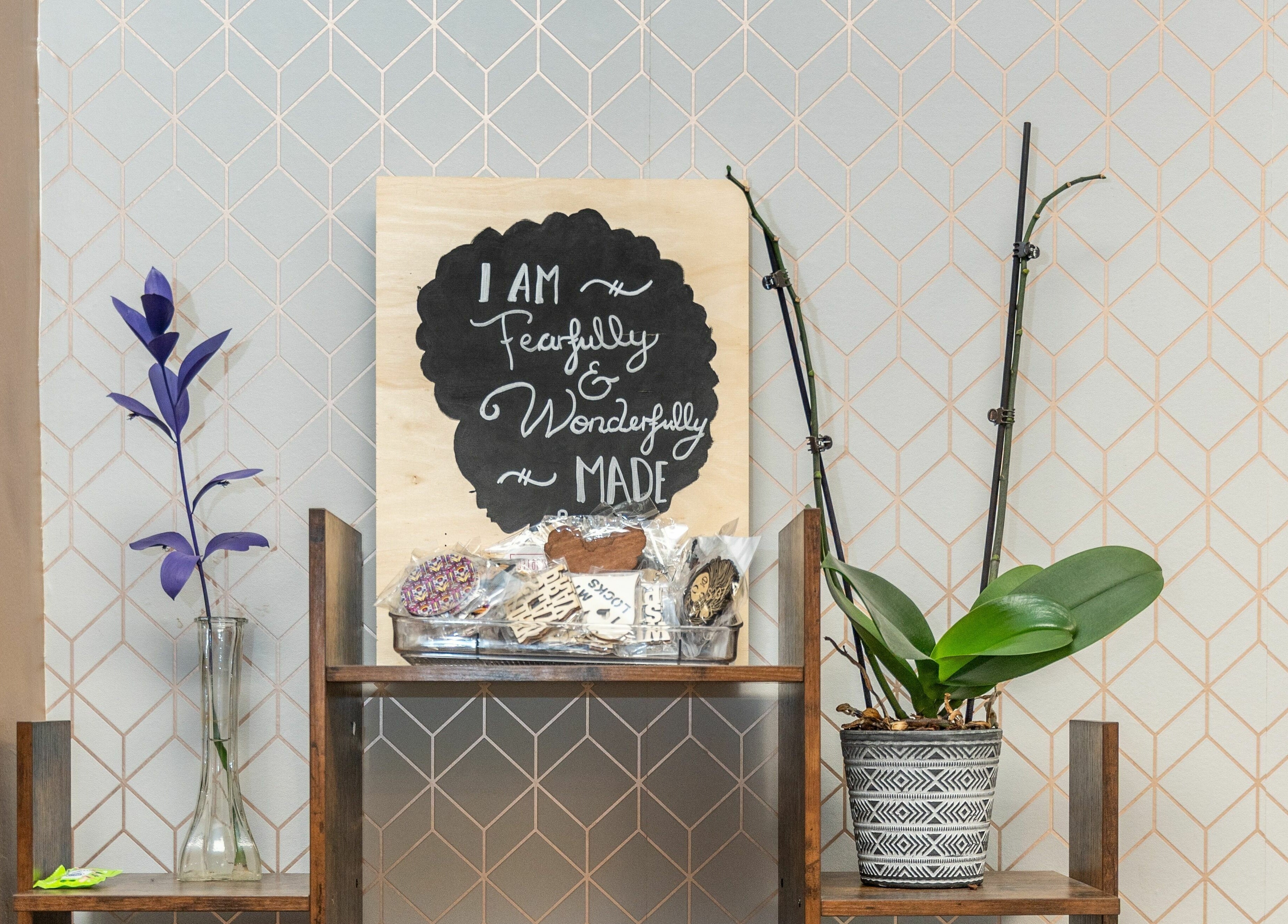 Chic shelf with uplifting sign and plants at Locs by Jiji in Toronto, Ontario, CA.