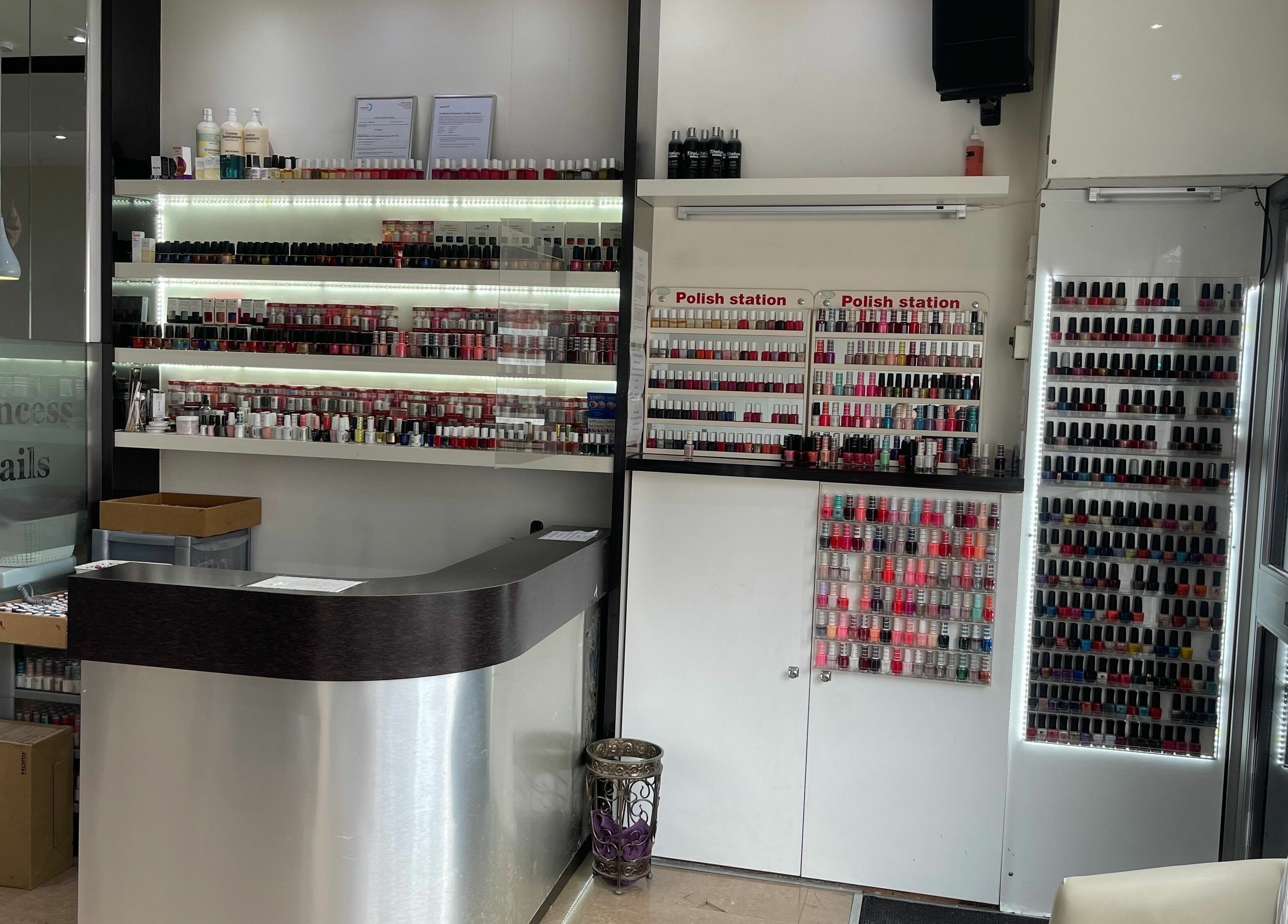 Interior of Princess Nails Wimbledon, showcasing a polished counter and extensive nail polish collection in London, England, GB.