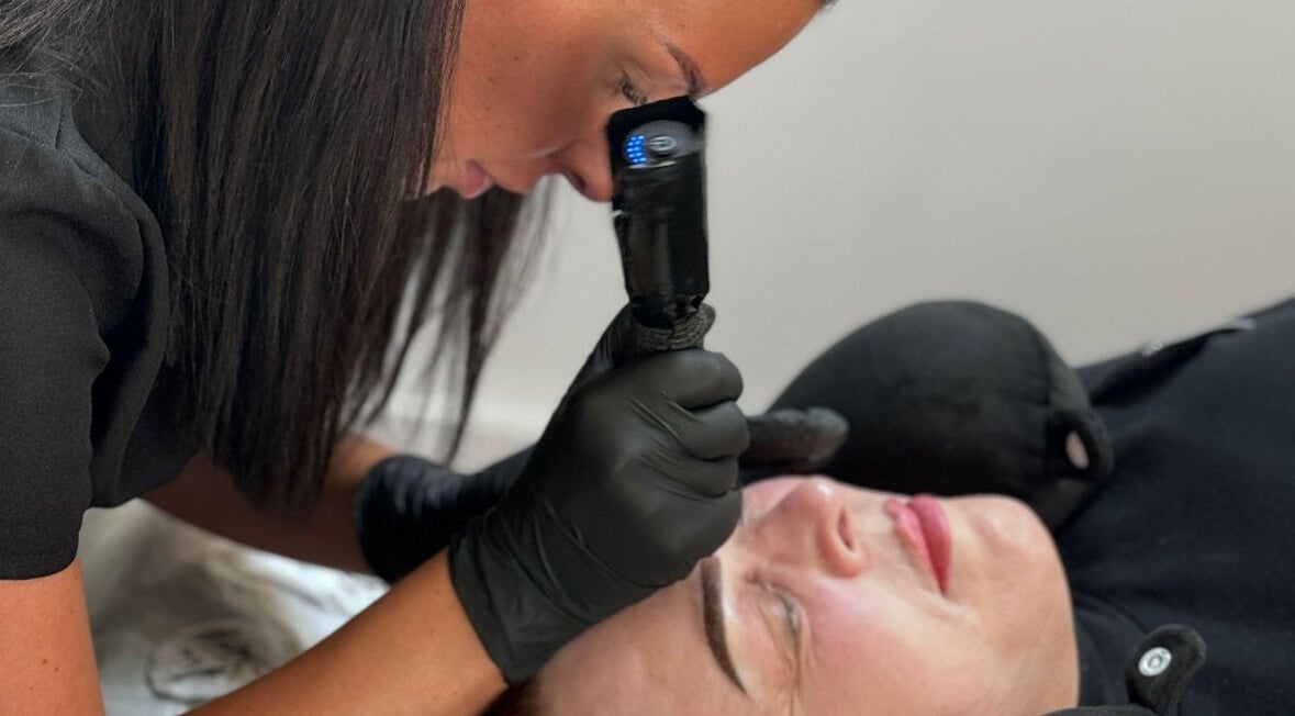 Beauty specialist at JALLONS in Clifton, England, GB, providing detailed facial care with precision tools.