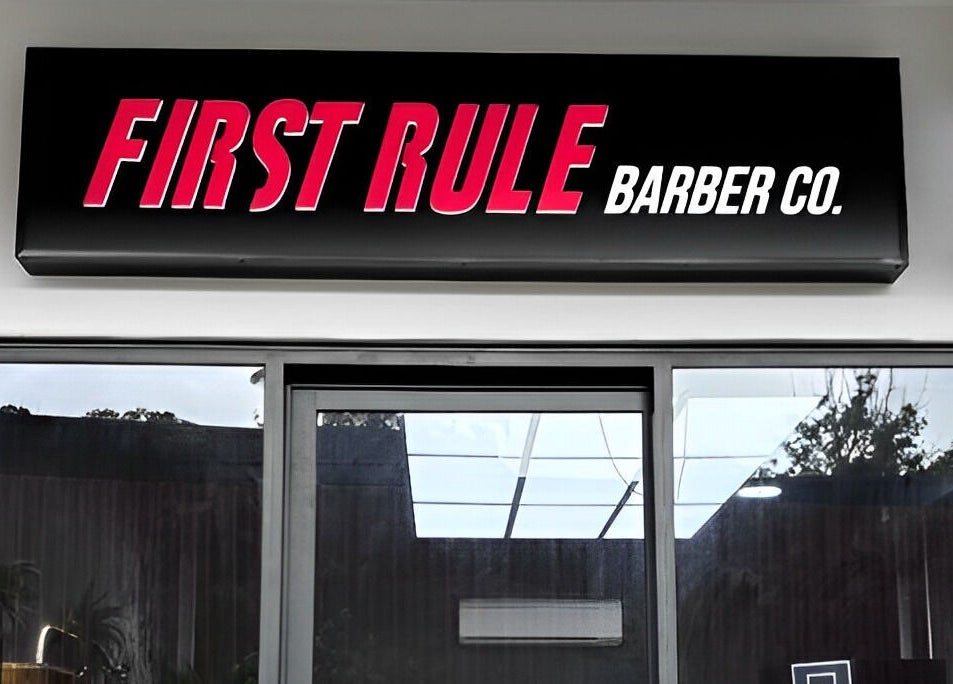 Exterior sign of First Rule Barber in Sippy Downs, Queensland, AU, featuring bold typography and a classic barber pole.