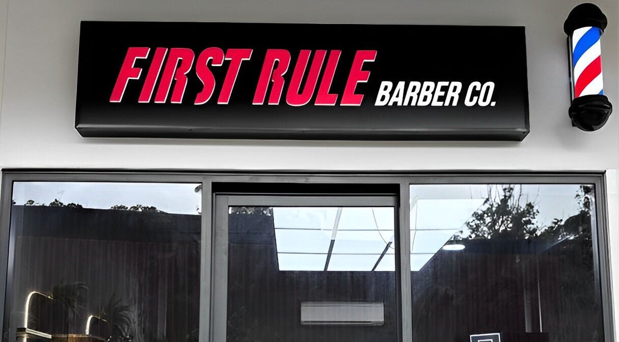 Exterior sign of First Rule Barber in Sippy Downs, Queensland, AU, featuring bold typography and a classic barber pole.