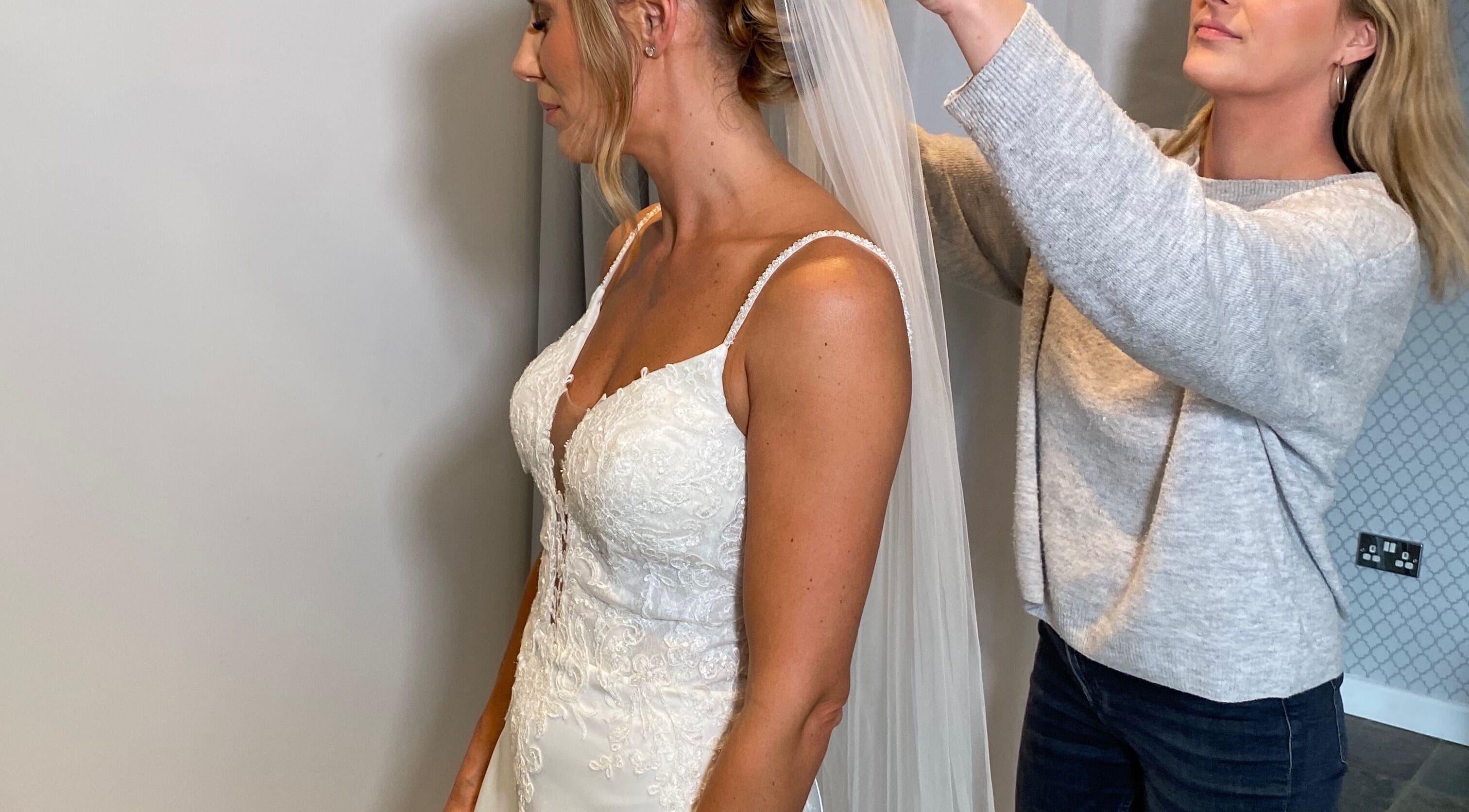 Stylist at Emma Lock Hair and Makeup in South Benfleet, England, GB, adjusts a bride's veil.