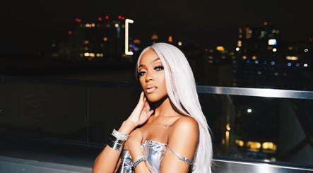 Elegant individual with long silver hair at Dame House Co., Stonecrest, Georgia, US, enjoying a night view.