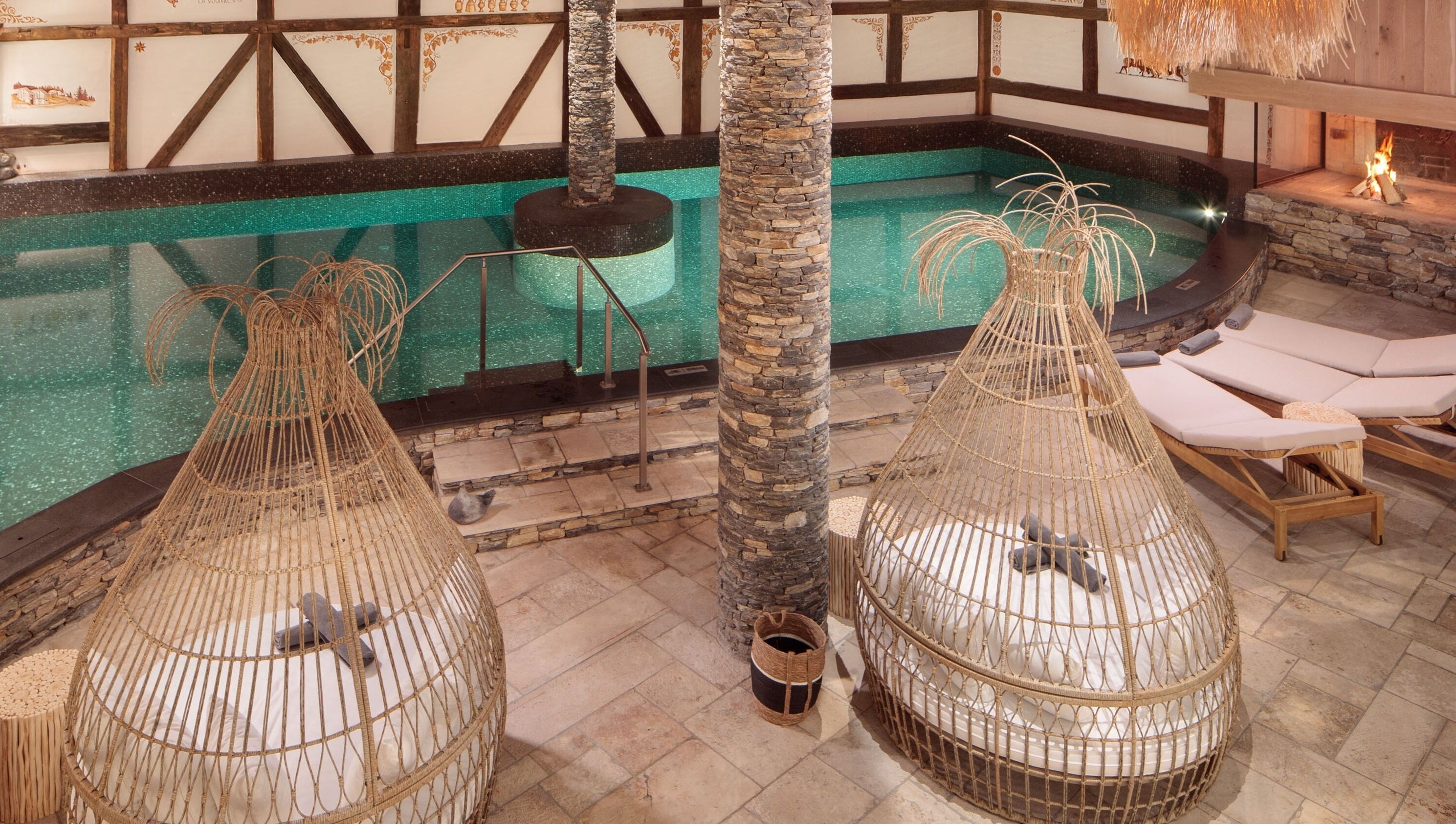 Piscine intérieure luxueuse de L'Aïda Hôtel and Spa à Crans-Montana, Valais, CH, entourée de transats élégants.