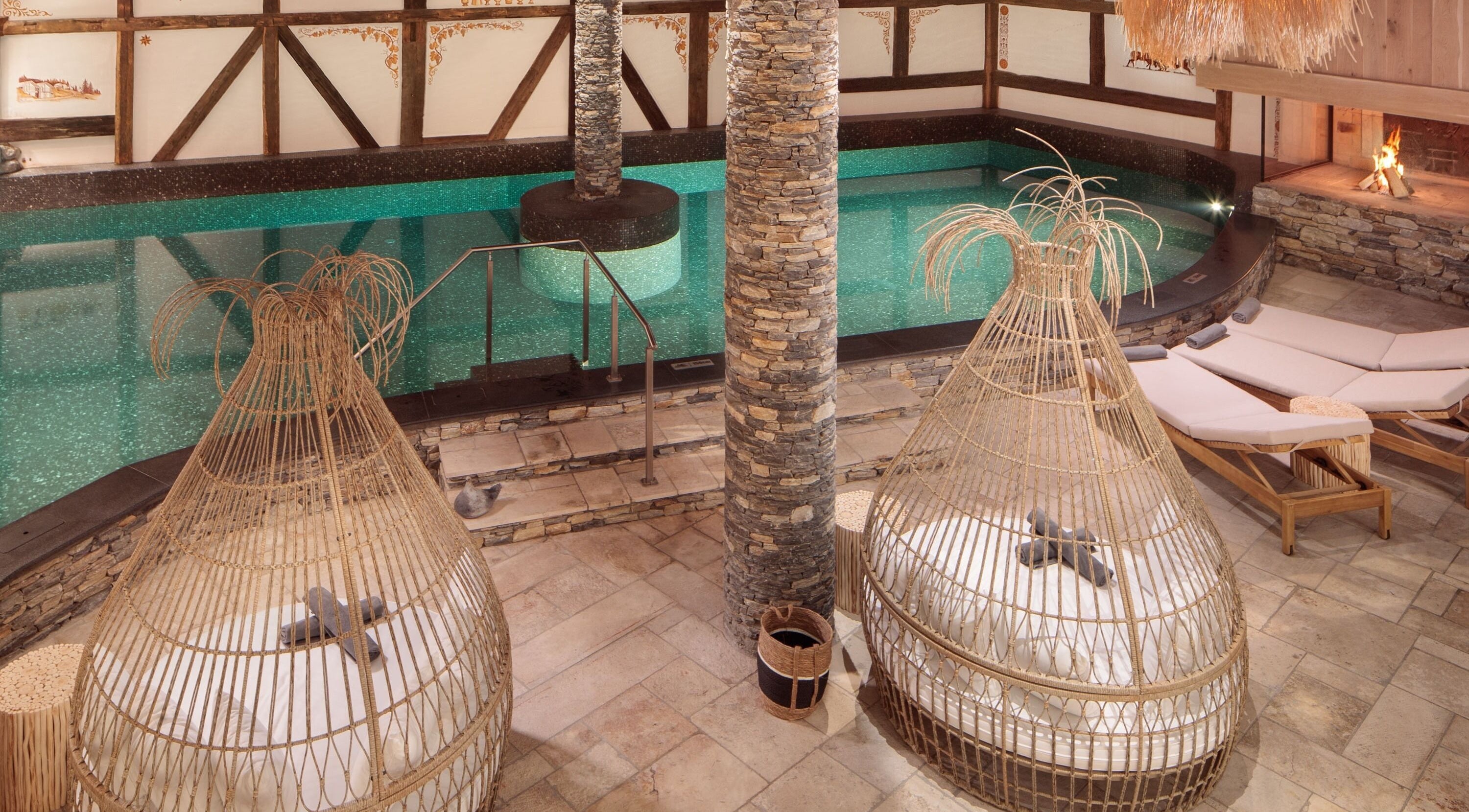 Piscine intérieure luxueuse de L'Aïda Hôtel and Spa à Crans-Montana, Valais, CH, entourée de transats élégants.