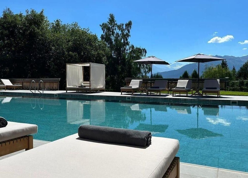 Piscine extérieure de L'Aïda Hôtel and Spa à Crans-Montana, Valais, CH avec vue sur les montagnes.