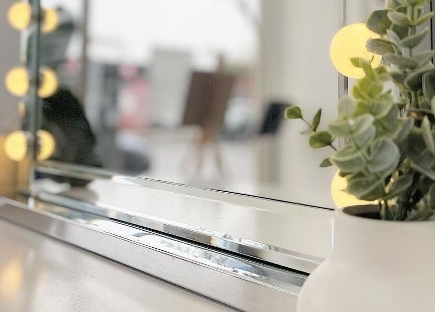 Elegant mirror with lights and plant at Salon Share Richmond, Richmond, Victoria, AU, enhancing the beauty space.