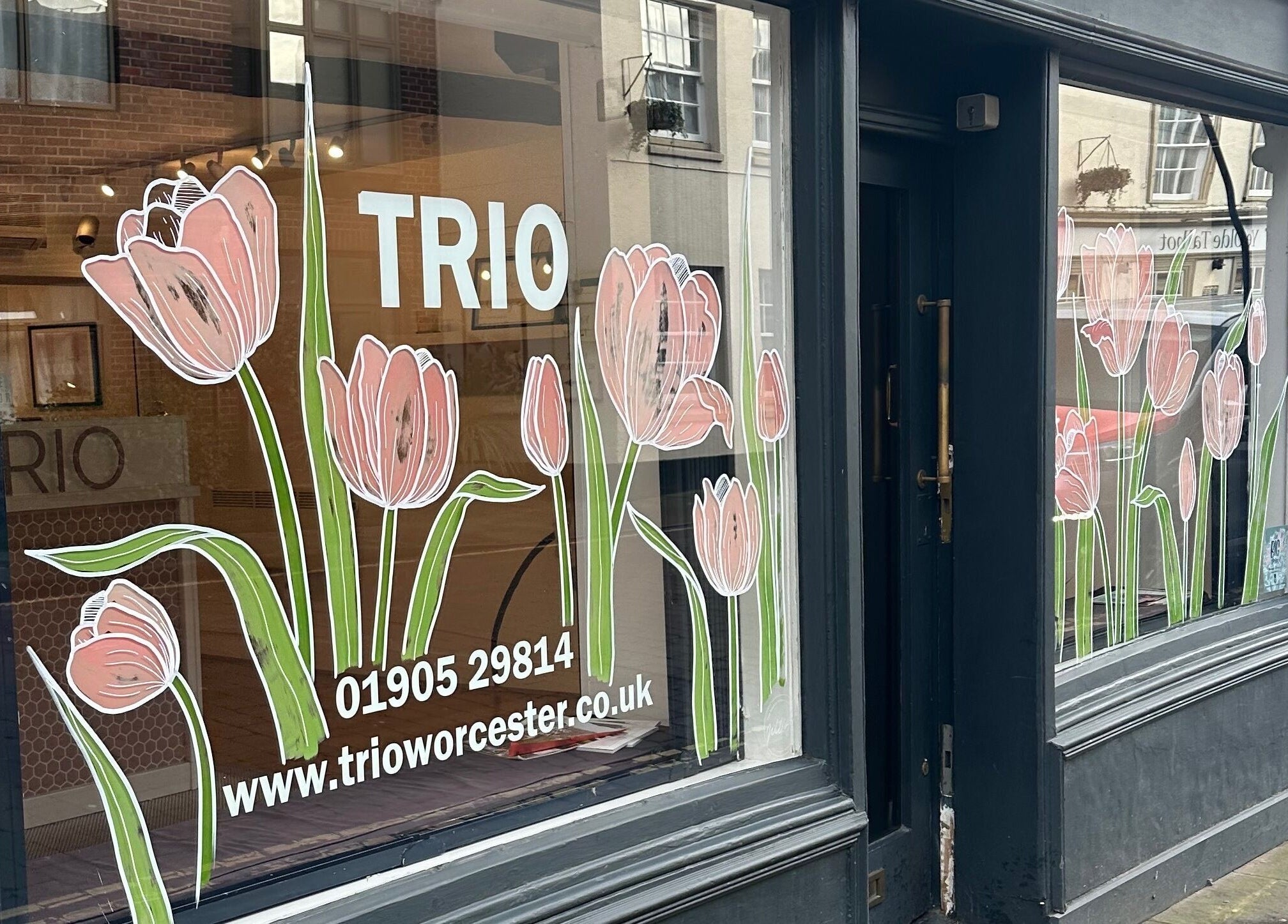 Front window of Trio Worcester adorned with pink tulip decals in Worcester, England, GB.