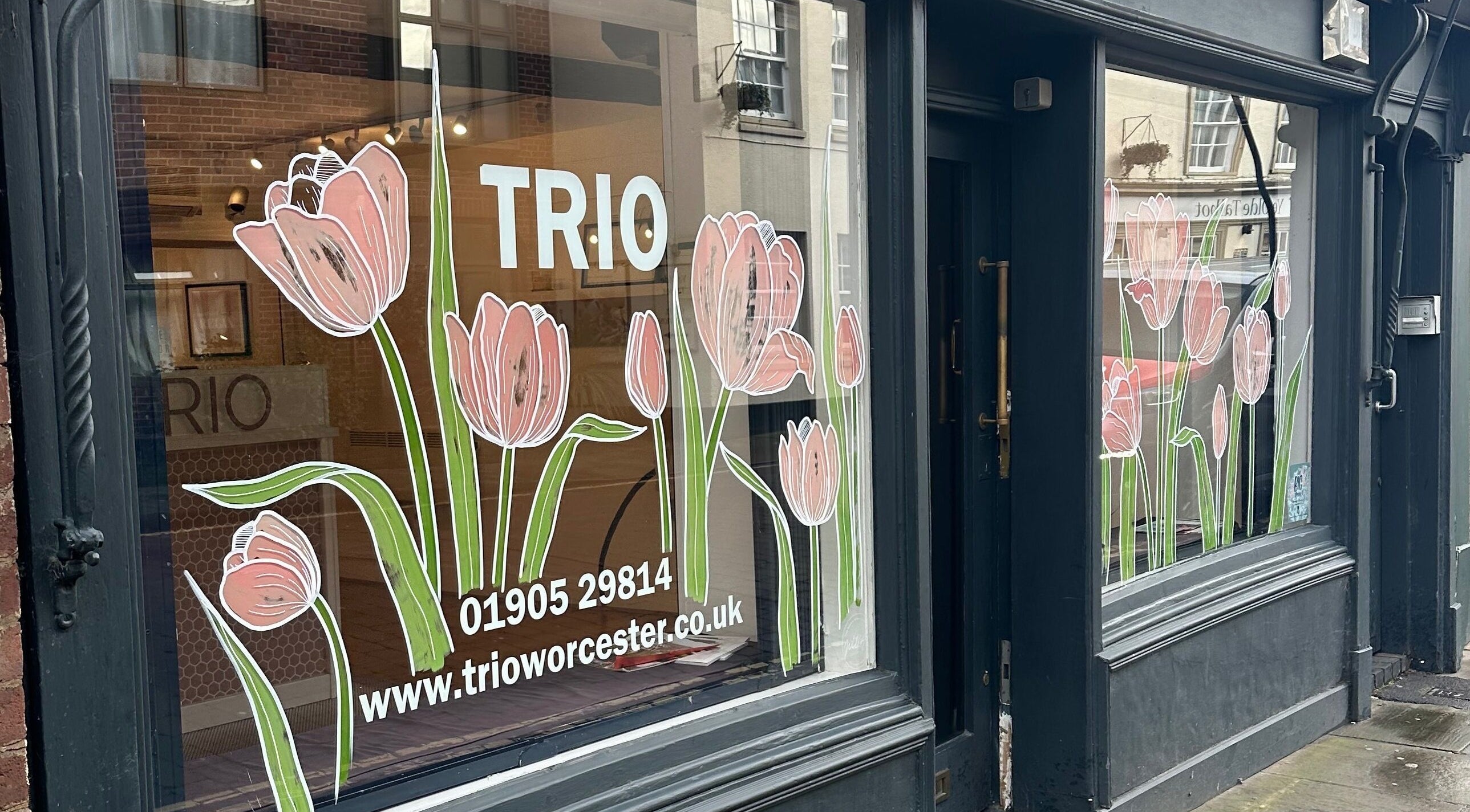 Front window of Trio Worcester adorned with pink tulip decals in Worcester, England, GB.