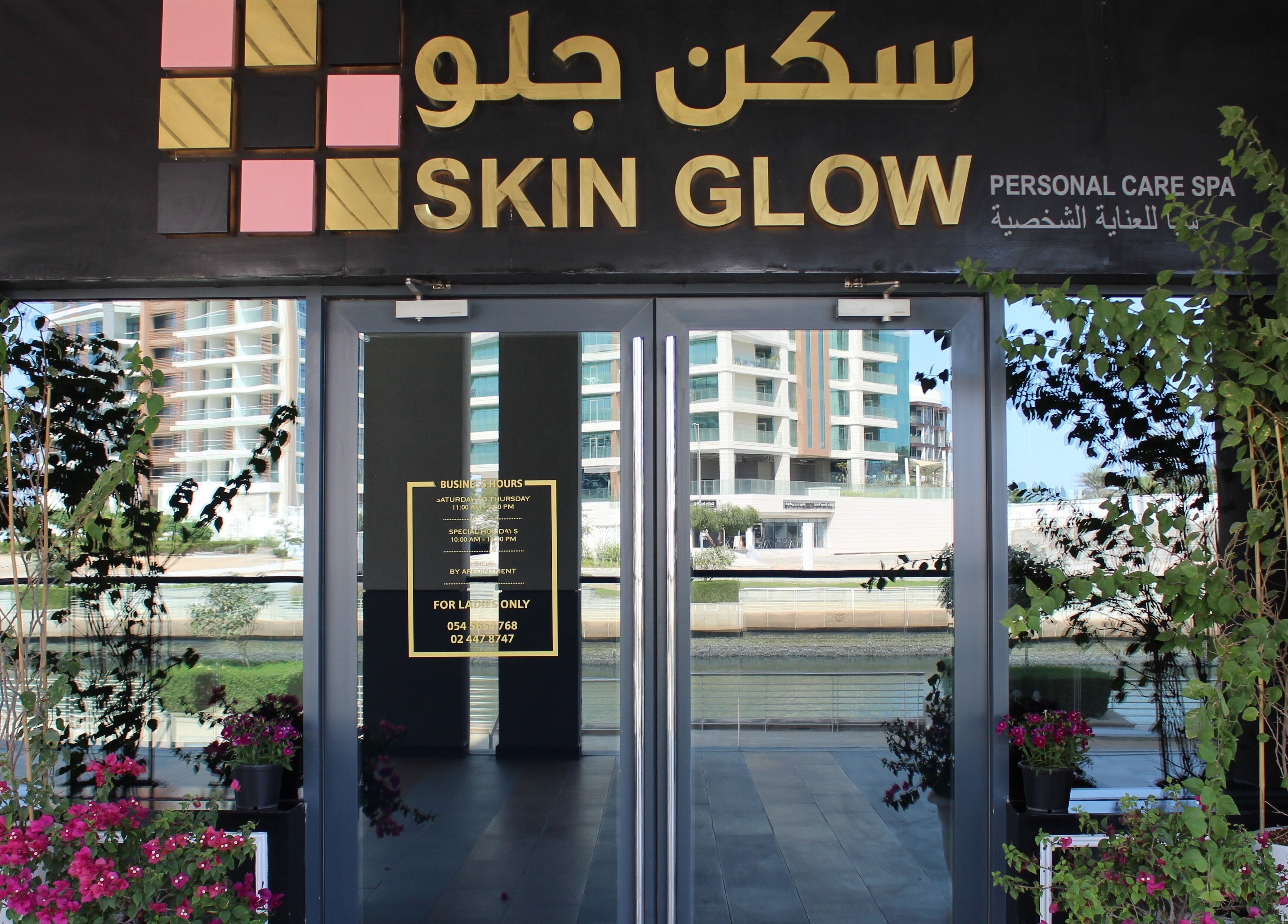 Entrance of Skin Glow Facial Center in Abu Dhabi, AE, beautifully adorned with lush greenery.