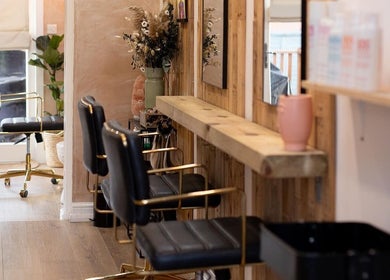 Chic interior of Carley Bayne Hair in Epsom, England, GB, featuring stylish chairs and wooden decor.