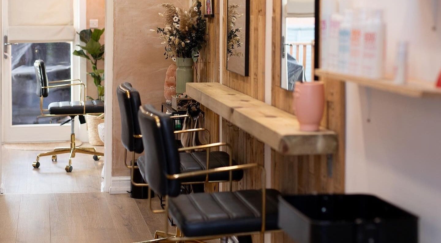 Chic interior of Carley Bayne Hair in Epsom, England, GB, featuring stylish chairs and wooden decor.