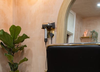 Modern styling station at Carley Bayne Hair, Epsom, England, GB with sleek hair tools and lush green plant.