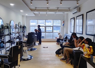 Interior modern dan nyaman di The Cut Rumah Barber Paskal, Jawa Barat, ID, menampilkan kursi dan pengunjung.