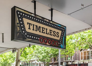 "Timeless Style" sign in Melbourne, Victoria, AU beneath leafy trees, showcasing a retro look.