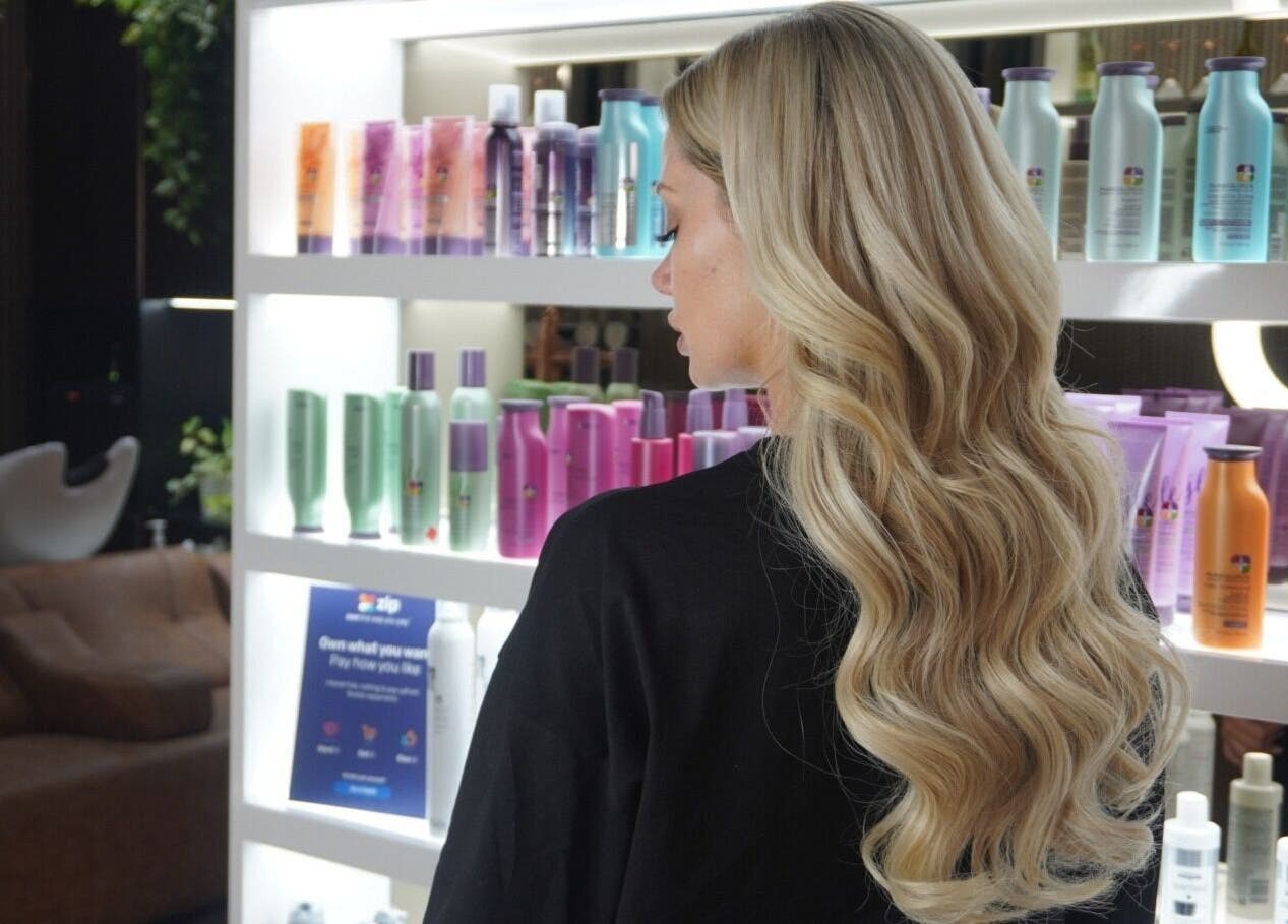 Blonde woman admiring hair products at Luppinos Boutique, West End, Queensland, AU.