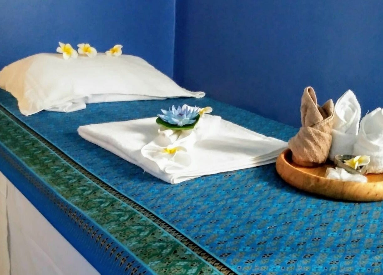 Letto da massaggio a The Thaiwells, Vicenza, Veneto, IT, con decorazioni floreali e tovagliette bianche.