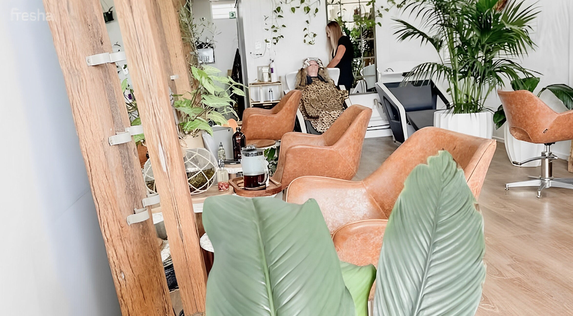 Relaxing interior of Cabello Hair and Beauty Bar, Coolangatta, Queensland, with chic chairs and greenery.