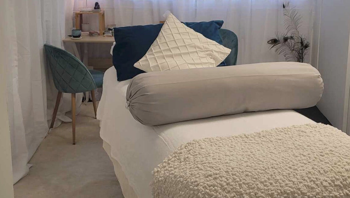 Relaxing treatment room at Metamorphosis Awakening in Tweed Heads, New South Wales, AU, featuring cozy bed and chair.