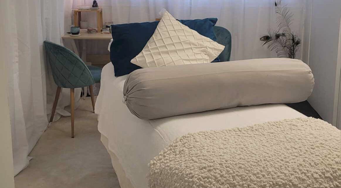 Relaxing treatment room at Metamorphosis Awakening in Tweed Heads, New South Wales, AU, featuring cozy bed and chair.