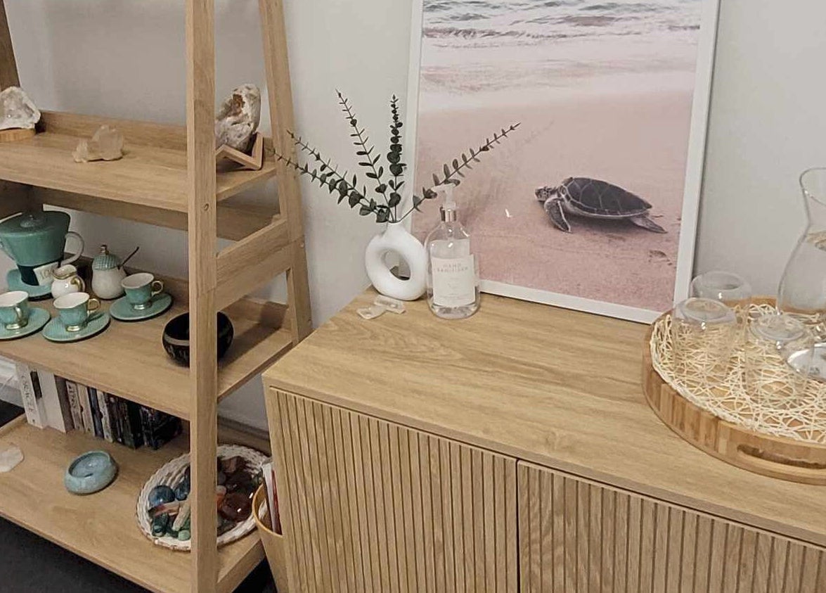 A serene corner at Metamorphosis Awakening, Tweed Heads, NSW, with a wooden shelf displaying teacups and crystals.
