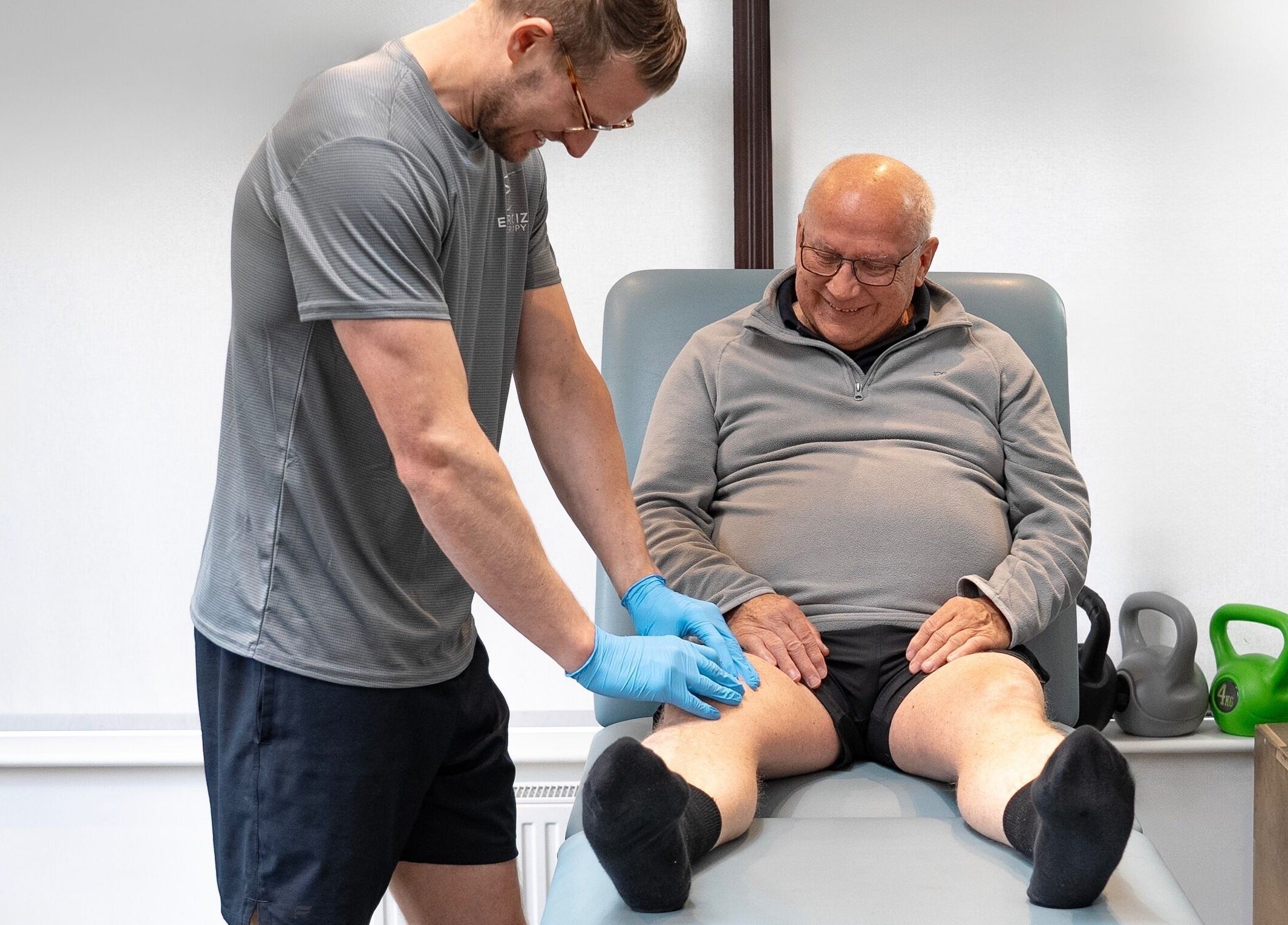 A wellness therapist at Energize Therapy in Droitwich Spa, England, GB, providing leg treatment for a client.