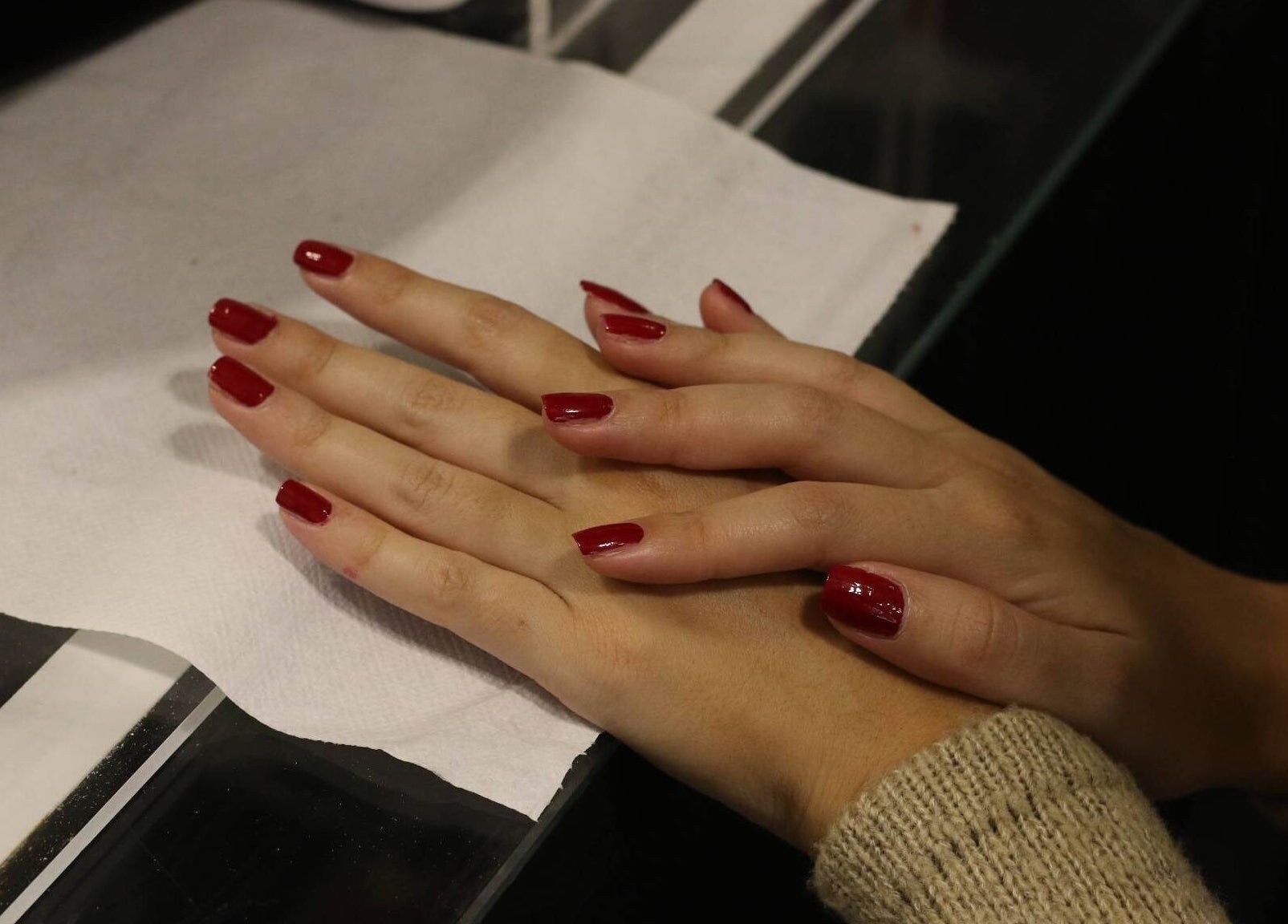 Manicured hands with red nails at Beauty Expressed in Colours, Marsascala, MT, highlighting artistry in detail.