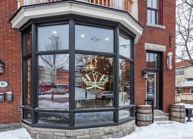 Cozy entrance of Blades & Bourbon in Gatineau, Québec, CA, with a classic barber pole and elegant window signage.