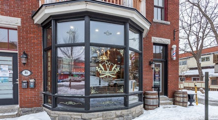 Cozy entrance of Blades & Bourbon in Gatineau, Québec, CA, with a classic barber pole and elegant window signage.