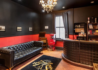 Blades & Bourbon reception area in Gatineau, Québec, CA. Features leather sofa, elegant decor, and vintage elements.