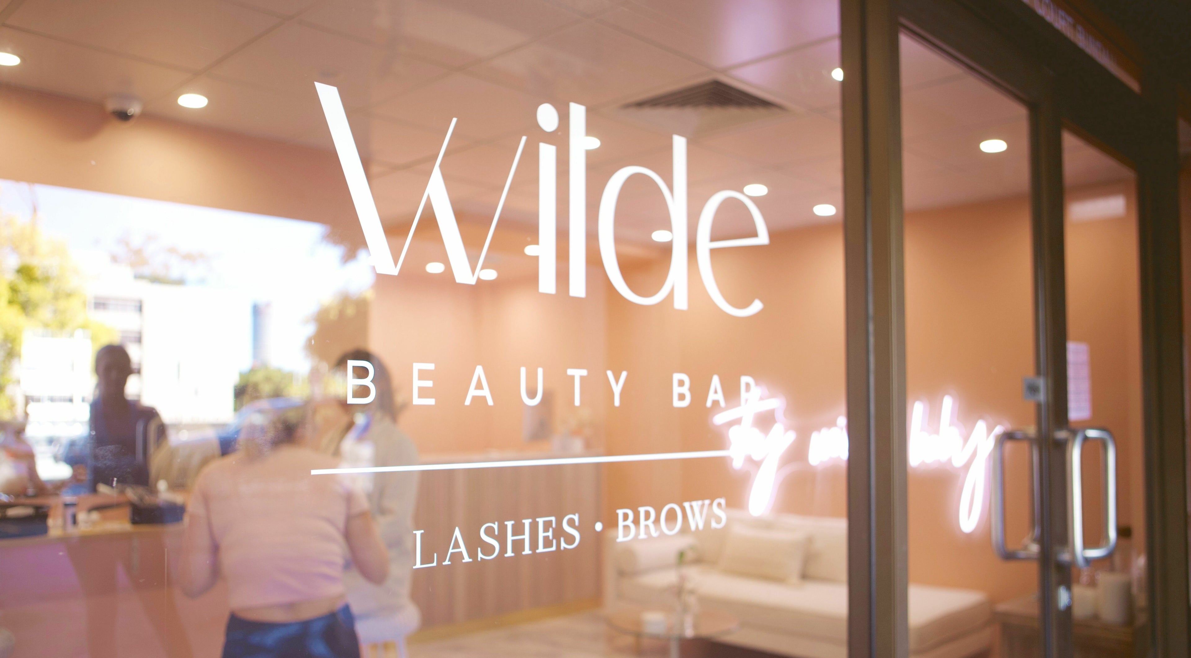 Entrance of Wilde Beauty Bar in Bundall, Queensland, AU featuring stylish logo on glass doors.